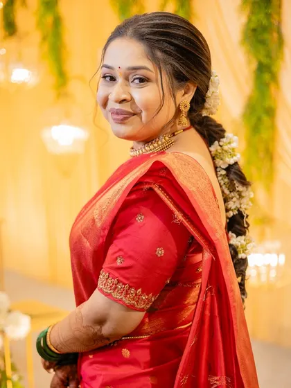A side profile of a bride in a red saree, highlighting her glowing skin and the beautiful gajra in her hair.