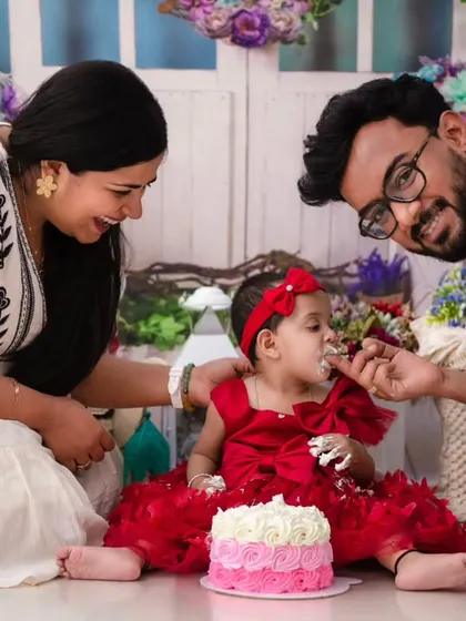 Celebrating a sweet milestone. A first birthday cake smash is more than a photoshoot, it is a memory of pure delight. Here, we see parents sharing in their daughter's first taste of birthday cake.