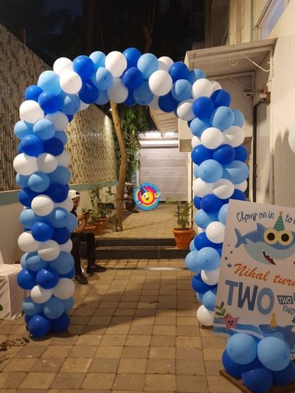 An entrance arch sets the tone for the party. For this Baby Shark theme, I built a large balloon arch in shades of blue and white, with a welcome sign inviting guests to "Chomp on in to celebrate".