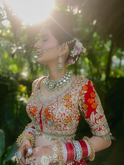The sun-kissed bride. The lens flare and backlighting create a magical, glowing effect, highlighting her profile and traditional nath.