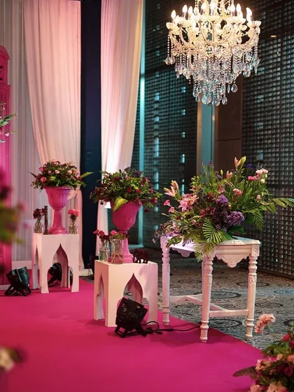 The pink telephone booth and chandeliers create a glamorous and whimsical atmosphere for the event.