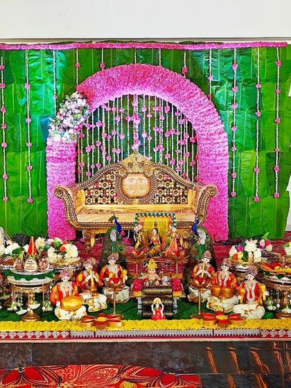 A baby shower setup with a green backdrop and a pink floral arch, creating a vibrant and festive atmosphere.