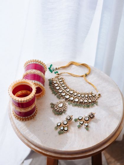 A beautiful flat lay of a bride's Polki jewelry set and her traditional red chooda.