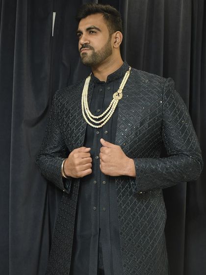 A client looking powerful in a dark, textured Indo-western jacket, accessorized with a multi-strand pearl necklace for a touch of royalty.