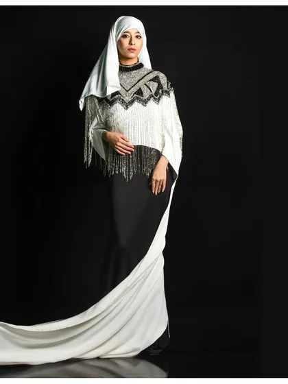 A powerful statement in monochrome. This shot features a modern, modest fashion ensemble against a stark black background, using the flow of the fabric to create a sense of motion and grace.
