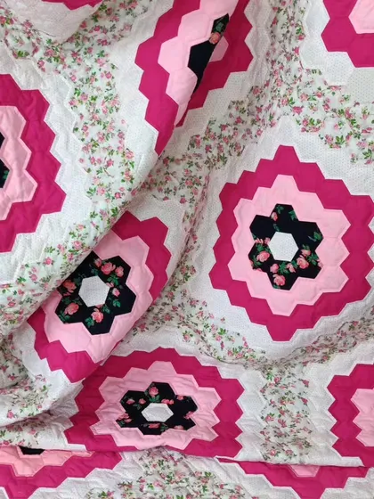 A close-up of the pink and black hexagon quilt.