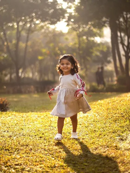 A little girl turning three, running freely in a sun-drenched park. Outdoor birthday shoots are perfect for capturing the boundless energy and joyful spirit of a toddler.