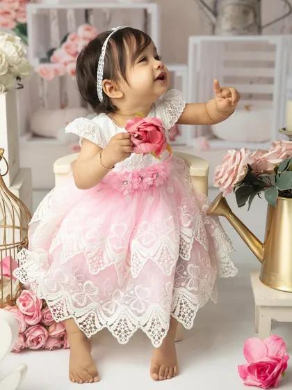 Looking up in wonder. This candid shot captures a moment of curiosity amidst the beautiful floral and white-washed wood backdrop of her cakesmash set.