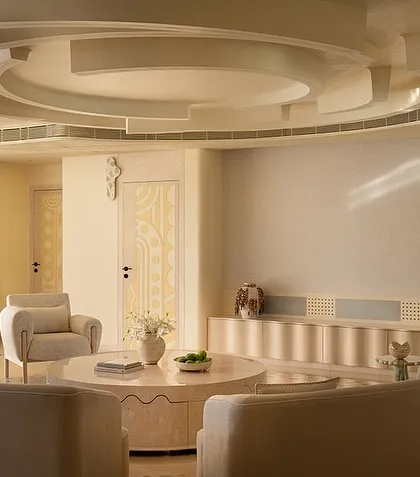 The living space in our 'Soft Serve' project is imagined as a series of intersecting circles. Curvilinear sofas and a sculptural ceiling design create a hypnotic visual of ripples and waves, all in a calming, ecru-toned palette.