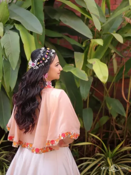A whimsical and romantic hairstyle for a Haldi carnival. This look features soft waves adorned with a custom floral and beaded headpiece, creating a beautiful bohemian vibe from the back.