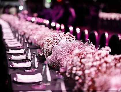 A close-up of the pink-lit tablescape, showing the beautiful floral runners and the unique, modern chairs.