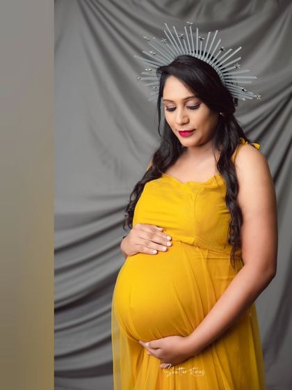 A close-up portrait focusing on the serene expression of the mom-to-be, her hand gently resting on her bump.