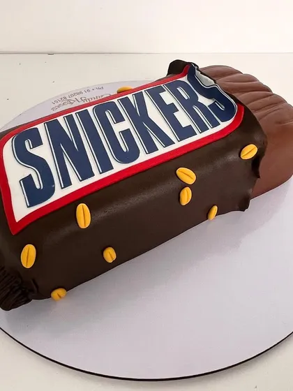 Another angle of the sculpted Snickers bar cake, showing the realistic wrapper and peanut details.