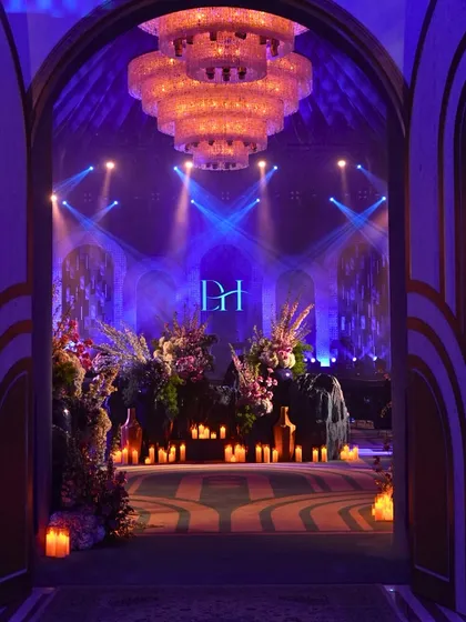For a 'Shaam Sufiana', I transform the venue into an atmospheric mehfil. This entrance, with its deep blue lighting, grand chandelier, and hundreds of candles, immediately set a mood of soulful elegance and intimacy.