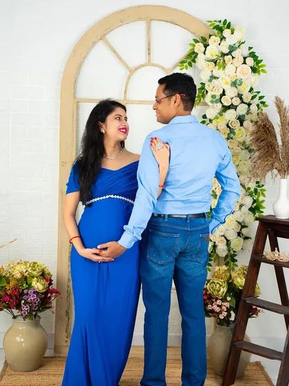 A loving gaze between partners. This couple's portrait, set against our floral archway, captures the deep connection and anticipation of parenthood.