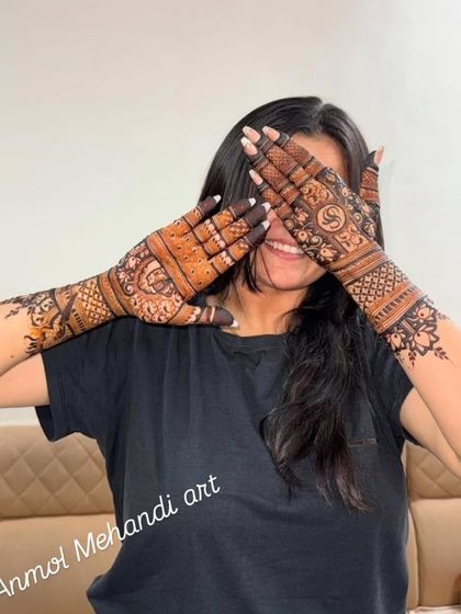A happy and playful client showing off her full-hand mehendi, a beautiful design with personalized initials.