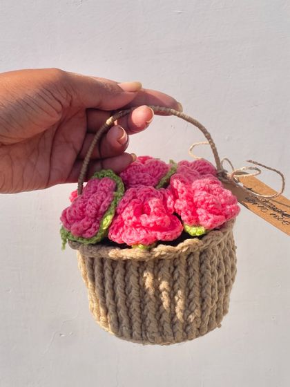 A mini basket full of pink roses. This adorable creation is a unique alternative to a traditional bouquet and a perfect piece of desk decor.