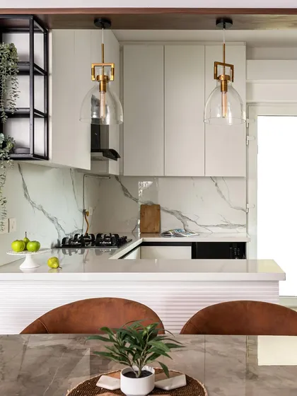 An all-white kitchen is timeless and always feels bright. This design features white handleless cabinets, a white quartz countertop, and a white marble-patterned backsplash, creating a clean and airy space.