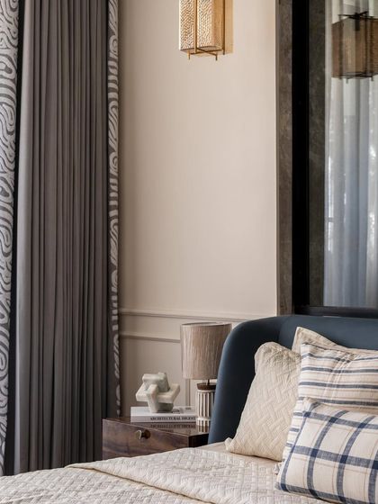 A detail shot showing the elegant patterned curtains and the plush, layered bedding. The combination of different textiles adds a luxurious and comfortable feel to the room.
