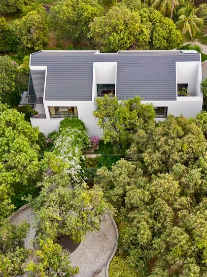 This aerial perspective highlights the home's unique T-shaped footprint and the way the driveway curves around a central cluster of trees. Our sustainable approach ensured not a single mango tree was cut during construction.