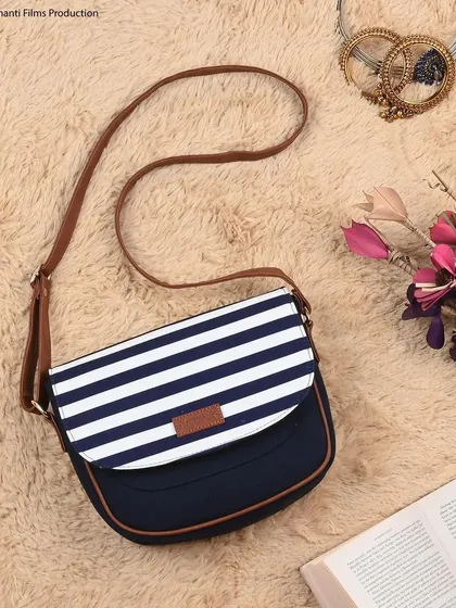 A creative flat-lay of a striped sling bag, styled with props like a book and flowers. This type of lifestyle image is perfect for website banners and Instagram feeds.