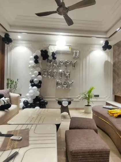 A minimalist and modern birthday setup for a living room. A simple black and white balloon half-arch and foil letters add a touch of celebration without overwhelming the space.