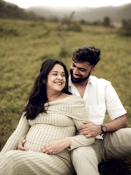 A happy, relaxed portrait of the couple sitting in a field. Their shared laughter and easy embrace show the joy and comfort they find in each other.