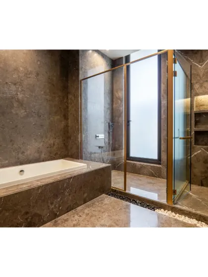 A view of the bathtub and shower area, both clad in the same rich, dark marble. The gold-tinted glass of the shower enclosure adds a touch of warmth and opulence.