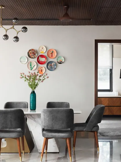 This dining space is personalized with a collection of decorative plates arranged as wall art. It's a simple yet effective way to add color and character, reflecting the homeowners' personality.