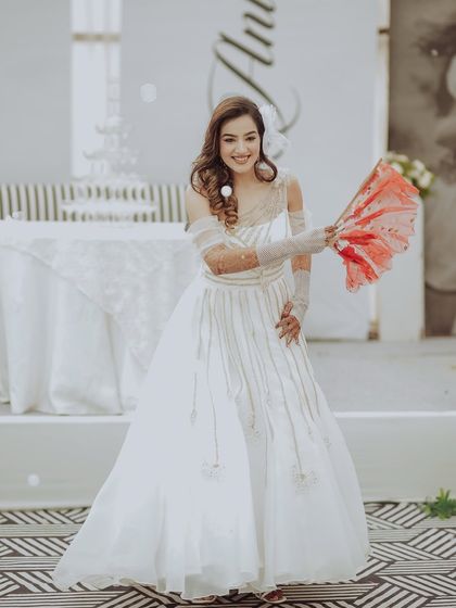 A playful and chic bridal portrait. The bride poses with a fan, her smile and the movement in her gown creating a fun and fashionable moment during the gala.