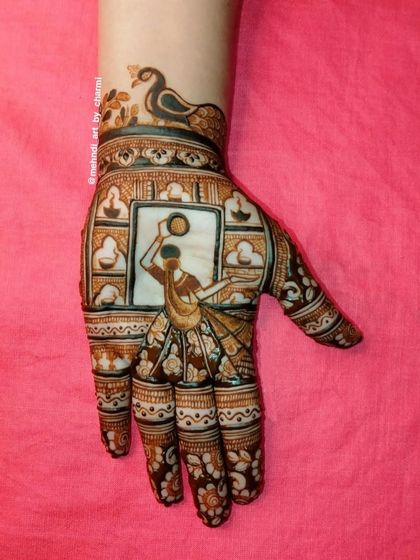 This design is perfect for a festive occasion, showing a woman carrying a pot of water (matka) surrounded by diyas. A peacock motif on the wrist adds a traditional touch.