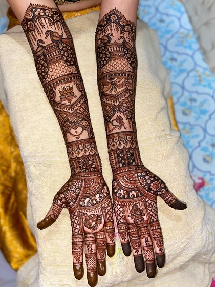 This design is filled with auspicious symbols, including peacocks, a crown, a heart, and a doli, creating a rich and meaningful bridal look.