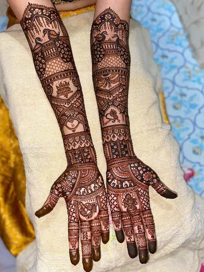 This design is filled with auspicious symbols, including peacocks, a crown, a heart, and a doli, creating a rich and meaningful bridal look.