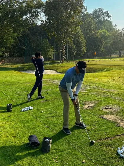 Two golfers practice side-by-side on the grass, focused and determined.