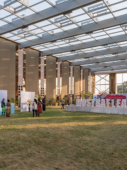 The interior of the Glass Pavilion, where a large, open lawn is sheltered by a 40-foot-high glass and steel structure. This design offers a unique experience, blending the comfort of an indoor hall with the feeling of being outdoors.