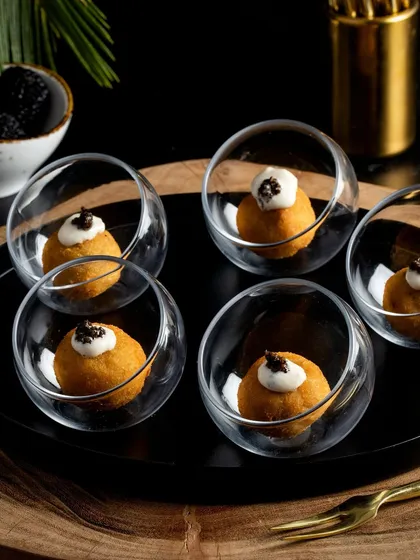 Creamy malai chicken croquettes infused with black truffle, served in individual glass bowls and topped with a dollop of cream and a hint of caviar.
