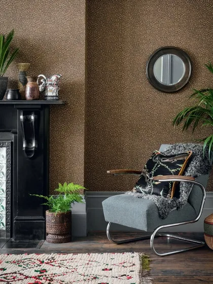 Cole & Son’s "Senzo Spot" wallpaper, inspired by giraffe spots, adds a playful yet refined charm to this cozy reading nook. The delicate metallic daubs on a rich brown background create a subtle texture and a touch of the wild.