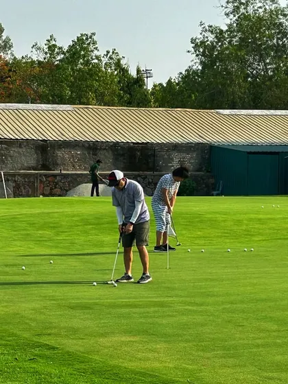 Two golfers work on their putting from different angles on our well-maintained green.