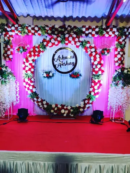 A classic engagement stage with a red and white theme. A large floral ring with a custom monogram serves as the central focal point.