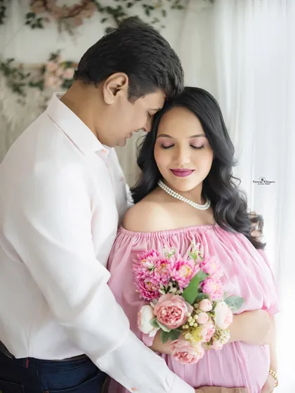 A close-up portrait capturing a moment of serene intimacy. The couple is lost in their own world, surrounded by soft light and delicate pink flowers.