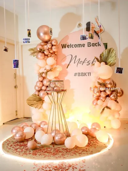 The complete welcome back setup, featuring rose gold balloons and a personalized photo display.
