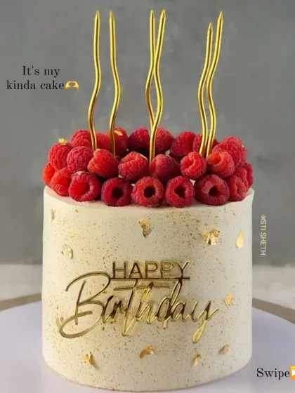 A close-up of the raspberry-topped cake, showing the fresh fruit and delicate gold candles.