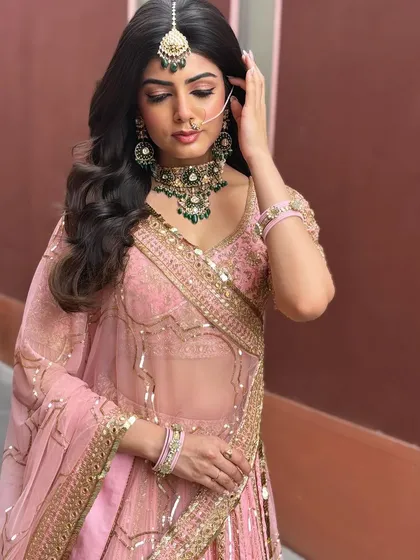 A full shot of the client in her pink lehenga, her open, wavy hair completing the romantic look.