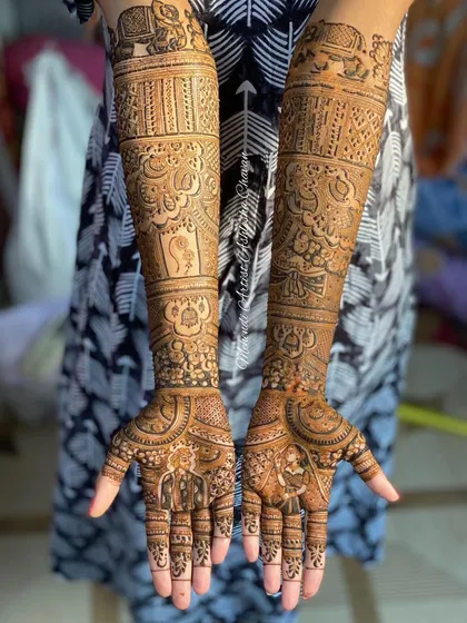 A full-arm bridal mehendi with a variety of traditional elements. The design includes elephants, kalash, and other auspicious symbols for the bride's new beginning.