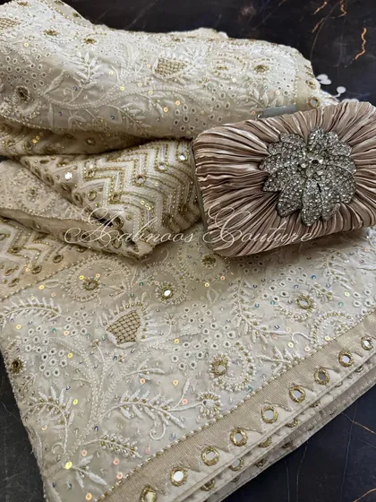 A styled shot of the folded saree with a jeweled clutch, suggesting a complete, glamorous look.