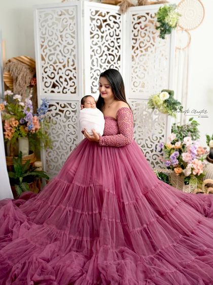 The first portrait of a mother and her newborn son. Her gentle gaze and the baby's peaceful sleep create a serene and loving moment against a beautiful floral backdrop.