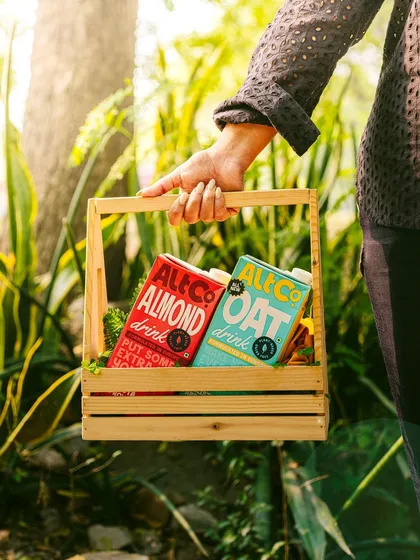 A person carrying a basket of Alt Co. almond and oat drinks. This "farmer's market" vibe creates a wholesome and aspirational image for the brand.