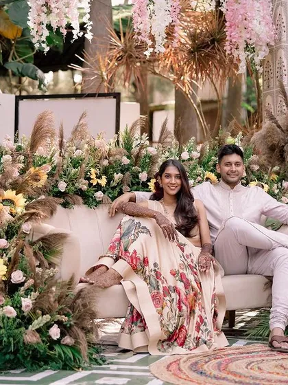 A happy couple posing at their beautiful boho-chic Mehendi, surrounded by pampas grass, sunflowers, and stylish decor elements.