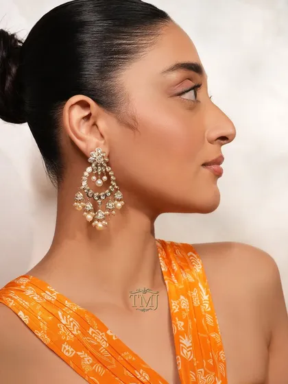 A wedding celebration is incomplete without the classic sparkle of chandbalis. This pair, featuring intricate polki work and delicate pearls, is designed to frame your face and add a touch of traditional glamour to your look.