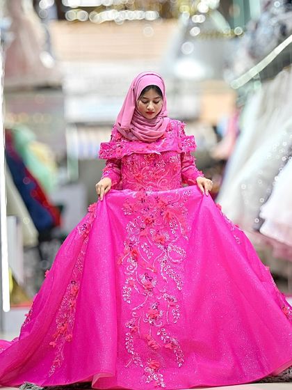 A closer look at the fuchsia ball gown, showing how the model is holding the voluminous skirt to showcase the incredible detail in the floral embroidery.